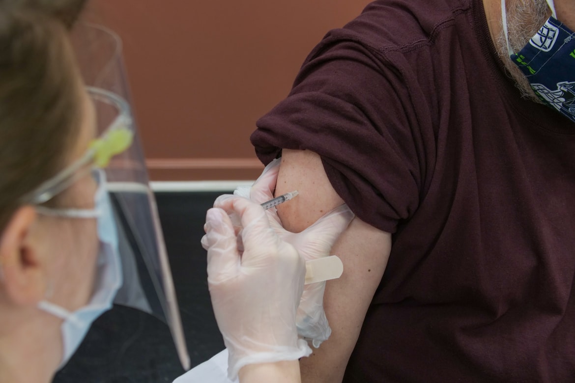 Une infirmière vaccinant un homme.
